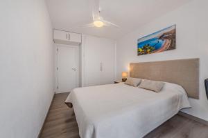 ein weißes Schlafzimmer mit einem Bett und einem Gemälde an der Wand in der Unterkunft Family flat with 3 bedrooms and balcony near Los Gigantes and ocean in Puerto de Santiago + 37 Fotos