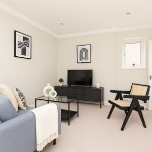 a living room with a blue couch and a tv at Spacious Flat in Prime Ealing in Ealing