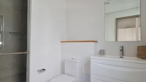 a white bathroom with a toilet and a sink at La Mivoie Beachfront Penthouse in Rivière Noire +8 photos