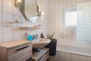 a bathroom with a sink and a tub and a mirror at Ferienwohnung Wilma Spetzerfehn in Großefehn  +25 photos