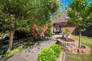 a garden with two trees and a brick walkway at Ferienwohnung Wilma Spetzerfehn in Großefehn 