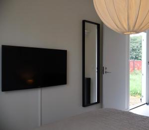 a flat screen tv on a wall next to a mirror at Cozy container, Österlen in Skillinge
