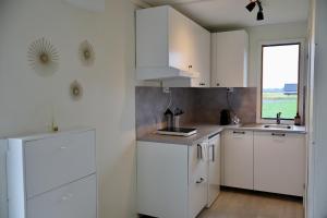 a white kitchen with white cabinets and a window at Cozy container, Österlen in Skillinge