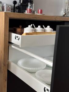 a kitchen cabinet with plates and dishes in it at Taki apartman in Debrecen
