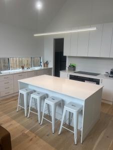a white kitchen with a large white table and stools at Laguna Beach House Ocean Grove-pets welcome in Ocean Grove +18 photos