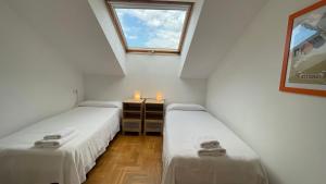 two twin beds in a room with a window at El Fuerte vacaciones para 5 personas con garaje wifi y petfriendly in Ribadesella