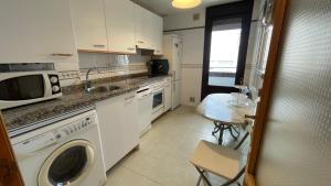 a kitchen with a washer and a table and a microwave at El Fuerte vacaciones para 5 personas con garaje wifi y petfriendly in Ribadesella