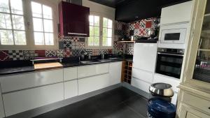 a kitchen with white cabinets and red and black tiles at Maison atypique familiale in Étaules +9 photos