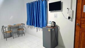 a room with a refrigerator and a tv on a wall at Route652 Resort Singburi in In Buri