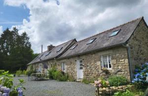 an old stone house with a table in front of it at La fermette de la vallee in La Chapelle-Neuve