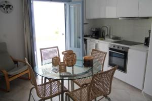 a kitchen with a glass table and some chairs at Iliada Suites Simousi Kythnos in Kithnos +35 photos