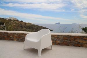 a white chair sitting on a balcony overlooking the ocean at Iliada Suites Simousi Kythnos in Kithnos