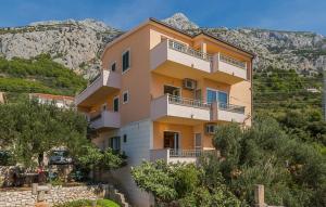 a building on a hill with mountains in the background at Apartman Tara - Makarska by Villas Guide in Makar