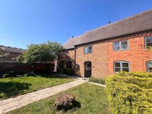 an old brick house with a grass yard at Barn Cottage in Binton