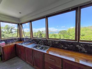 a kitchen with a sink and a bunch of windows at The Nest in Coron