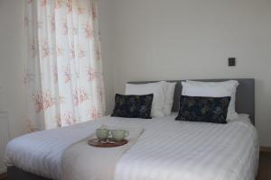 a bed with two cups and a tray on it at Estrela Do Norte in De Cocksdorp