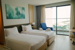 two beds in a hotel room with a balcony at Sea View Standard Room in The Arena Resort Cam Ranh in Cam Ranh International Airport +36 photos