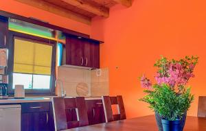 una cucina con pareti arancioni e un tavolo con un vaso di fiori di Amazing Home In Podamirowo a Podamirowo