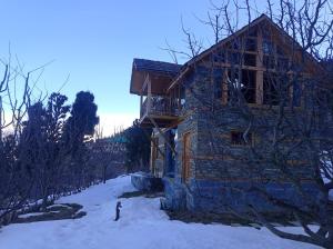 Cette cabane en rondins dispose d'un balcon dans la neige. dans l'établissement Shantchit Wellness Resort Hotel in Kasol Valley, à Kasol