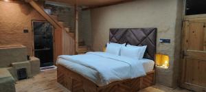 une chambre avec un grand lit avec des draps blancs dans l'établissement Shantchit Wellness Resort Hotel in Kasol Valley, à Kasol