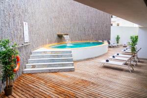a swimming pool with a fountain on a wooden floor at Villa Doris Suites in Lagos
