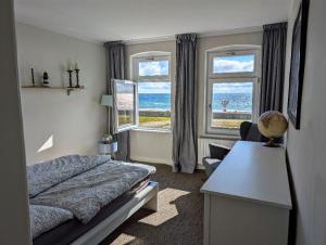 a bedroom with a bed and a desk and two windows at Haus am Meer- Traumhafter Meerblick in Dahme