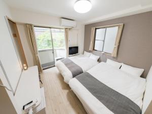 two beds in a room with two windows at Ikebukuro 10 min-Family-Friendly Stay-Mobile Wi-Fi&Switch-Net in Tokyo