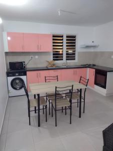 eine Küche mit rosa Schränken sowie einem Tisch und Stühlen in der Unterkunft Pink des îles in Saint-François