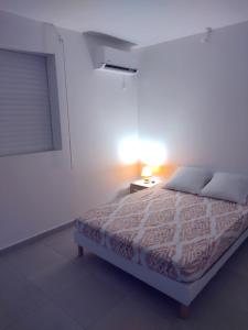 ein Schlafzimmer mit einem Bett und einer Lampe auf einem Tisch in der Unterkunft Pink des îles in Saint-François