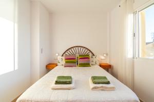 a white bedroom with a bed with towels on it at Cómodo apartamento en El Calón Playa frente al mar in El Calón +44 photos