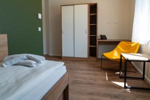 a bedroom with a bed and a yellow chair at MEDIGREIF Elternhaus Setheweg GmbH in Heringsdorf