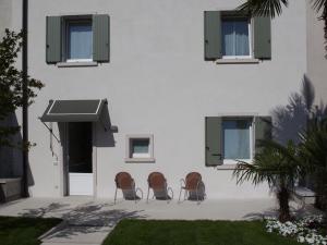 three chairs sitting in front of a building with windows at Corte Mantovani in Colà di Lazise