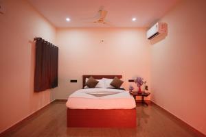 a bedroom with a bed and a tv on the wall at Hotel Pergola - Mysore in Chāmundi +8 photos