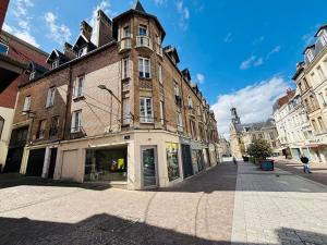 a large brick building with a clock tower on a street at Le Saint André Hyper centre ville in Saint-Quentin