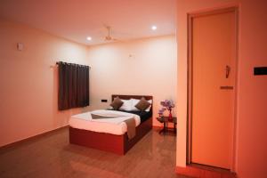 a bedroom with a bed and a door to a room at Hotel Pergola - Mysore in Chāmundi