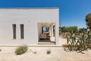 a white house in the desert with a cactus at Paradise Villa Torre Guaceto in Carovigno