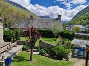 a house with a garden and mountains in the background at Maison La Flambée in Bordères-Louron