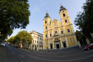 a yellow building with a clock tower on a street at Taki apartman in Debrecen