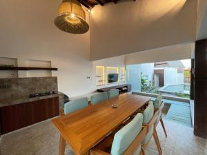 Tanah Lot Dreams Complex Villas By GUMA Hospitality في تاناه لوت: غرفة طعام مع طاولة وكراسي خشبية