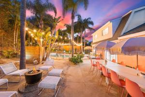 a patio with tables and chairs and palm trees at Dream Stay! Pool, Hot Tub, PacMan,Foosball and More! in Oceanside