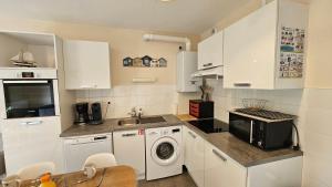a kitchen with white cabinets and a washer and dryer at Appartement Capsea 4 étoiles, St Valery-sur-S, avec 2 parkings gratuits in Saint-Valery-sur-Somme