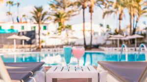 two wine glasses sitting on a table next to a swimming pool at Labranda Marieta & Spa - Adults Only in Playa del Ingles