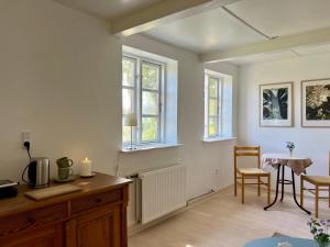a living room with a table and chairs and windows at Noorbohandelens Bed & Breakfast - Nyord in Stege