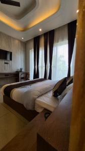 a bedroom with a large bed with a large window at The Corbett Green Woods in Rāmnagar +6 photos