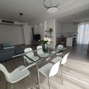 a dining room with a glass table and white chairs at Tonfano Waterfront Penthouse in Marina di Pietrasanta +2 photos