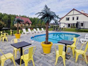 a patio with tables and chairs next to a pool at Mazurskie Wzgórze BIS z basenem in Rydzewo