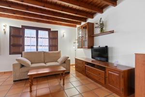 a living room with a couch and a tv at Apartamentos El Rincón de Bustio in Bustio