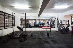 une salle de sport avec plusieurs machines à bande de roulement et un banc rouge dans l'établissement The Cozy house, à Nairobi
