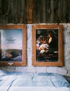 two posters on a wall next to a bed at Ulęgałki Roztocze Stodoła in Jacnia