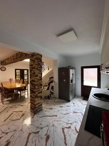 a kitchen and dining room with a table and a brick fireplace at Casa Luminița in Vama Buzăului